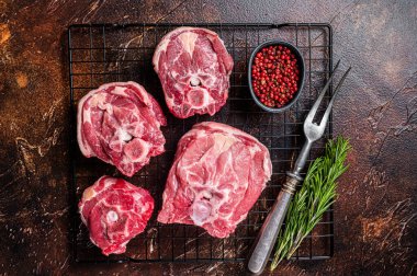 Fresh Raw lamb neck meat slices, mutton meat on a rack with herbs. Dark background. Top view.