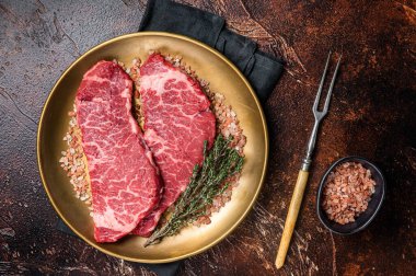 Alternative beef steak Denver, raw meat steak with herbs. Dark background. Top view.
