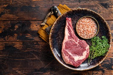 Raw prime cowboy or rib eye steak, dry aged beef meat. Wooden background. Top view. Copy space.