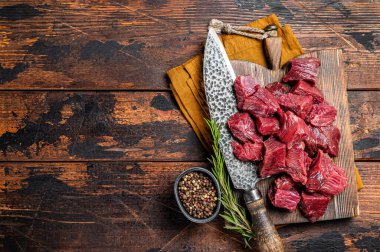 Sliced Raw venison dear meat for a stew, game meat on butcher cutting board. Wooden background. Top view. Copy space.