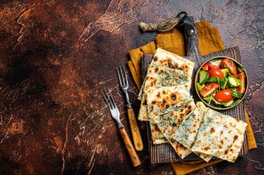 Freshly baked Turkish Gozleme, flatbread with greens and cheese. Dark background. Top view. Copy space.