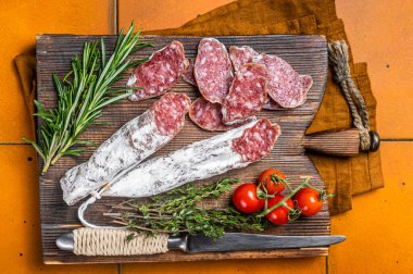 Spanish Fuet sausage slices on wooden cutting board. Orange background. Top view.