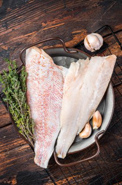 Raw red perch fillet, redfish fish meat in a steel tray. Wooden background. Top view.