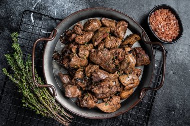 Kızarmış tavuk ciğeri, soğan ve otla birlikte. Siyah arka plan. Üst görünüm.