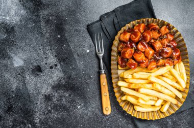Alman körili sosisi ve patates kızartması çelik tabakta servis ediliyor. Siyah arka plan. Üst Manzara. Boşluğu kopyala.