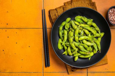 Deniz tuzu ve susam tohumlu haşlanmış Edamame Soya fasulyesi. Turuncu arka plan. Üst Manzara. Boşluğu kopyala.