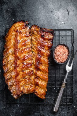 BBQ grilled pork spare ribs on a rack. Black background. Top view.