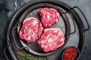Raw lamb neck meat with bone on a steel tray. Black background. Top view.