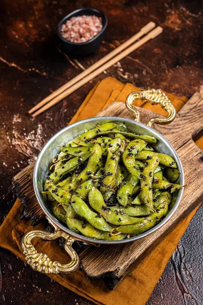 Roasted green Edamame Soy Beans with sea salt and sesame seeds in a skillet. Dark background. Top view.