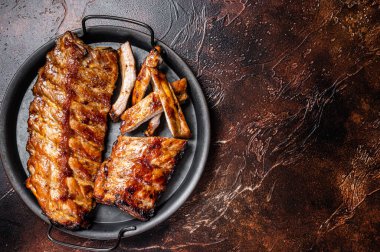 BBQ pork spare ribs St Louis with hot honey marinade in a steel tray. Dark background. Top view. Copy space.