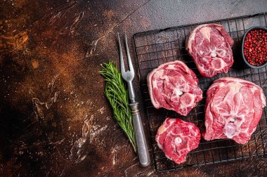 Fresh Raw lamb neck meat slices, mutton meat on a rack with herbs. Dark background. Top view. Copy space.