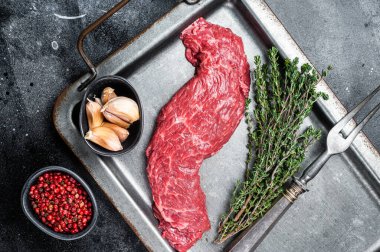 Raw fresh meat Steak Machete, skirt with thyme on steel tray. Black background. Top view.