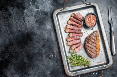 Kızarmış ve dilimlenmiş Top sığır filetosu bifteği, ızgara biftek çelik servis tepsisinde baharatlı biftek. Siyah arka plan. Üst Manzara. Boşluğu kopyala.