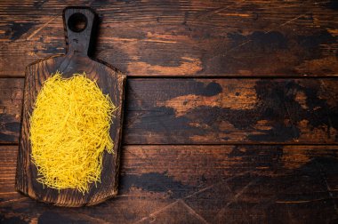 Vermicelli makarna, ahşap bir tahtanın üzerinde çiğ çiğ. Siyah arka plan. en üstteki görünüm.