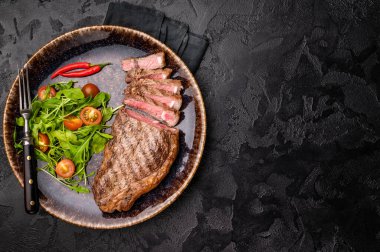 Izgara çizgili biftek, salatalı biftek. Siyah arka plan. en üstteki görünüm.