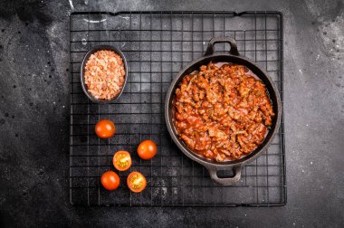 Kıymalı bolonez sosu, domates ezmesi ve tavada otlar. Siyah arka plan. en üstteki görünüm.