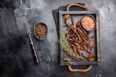 Etli börek, kızarmış sığır eti şeritleri, tepside dilimlenmiş et. Siyah arka plan. en üstteki görünüm.