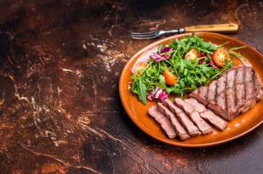 Izgara Avustralya istiridye üstü bıçaklı biftek ve tabakta salata. kahverengi arka plan. en üstteki görünüm.