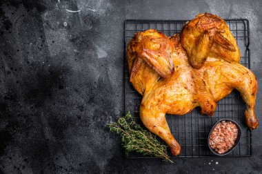 Ot ve baharatlı kızarmış Spatchcock tavuğu, çelik rafta kümes hayvanları eti. Siyah arka plan. en üstteki görünüm.