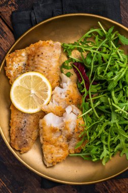 Kavrulmuş Pollock balığı filetosu ve salata. Ahşap arka plan. en üstteki görünüm.
