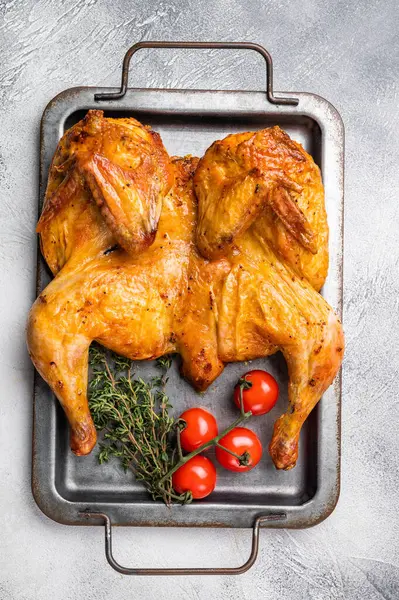 Baharatlı fırında tavuk Tabaka, çelik tepside kümes hayvanı eti. Beyaz arka plan. en üstteki görünüm.