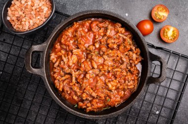 Kıymalı bolonez sosu, domates ezmesi ve tavada otlar. Siyah arka plan. en üstteki görünüm.