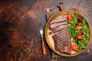 Kurutulmuş sığır etli biftek ve salata. kahverengi arka plan. en üstteki görünüm.