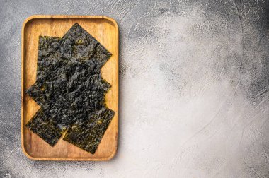 Tahta tepside çıtır çıtır Nori yosun çarşafları. Beyaz arka plan. en üstteki görünüm.