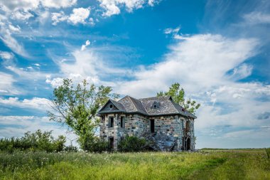 Abernethy, SK dışındaki Saskatchewan ovalarında ağaçlarla çevrili terk edilmiş bir taş ev.