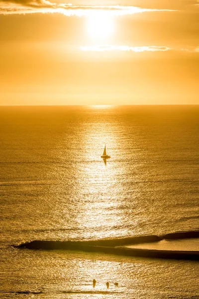 Sunset over a single sailboat off Magic Island on Oahu, Hawaii