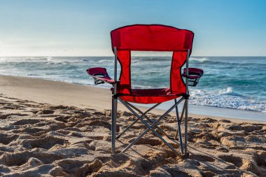 An empty red beach chair facing the water on Sunset Beach, Hawaii 