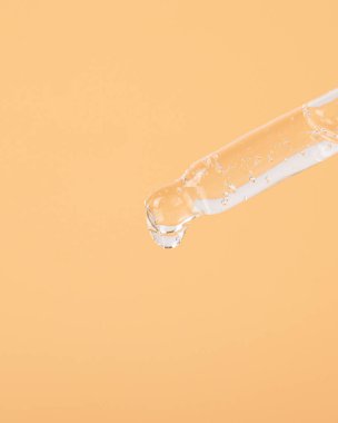 Sarı arka planda bir damla yağlı pipet.