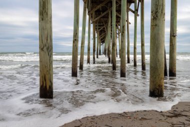 Waves crashing under the pier at Carolina Beach in North Carolina