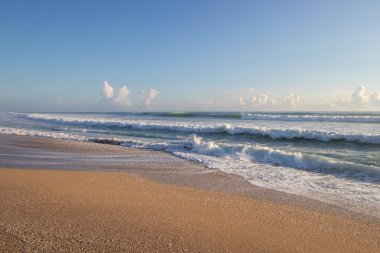 Güzel bir yaz sabahında kumlu bir plaja düşen dalgalar.