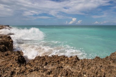 Güzel turkuaz tropikal suyla kayalık sahilde dalgalar kopuyor.