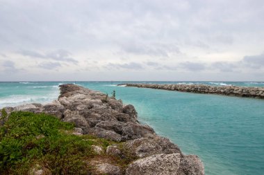 Bulutlu bir günde okyanus körfezi. İskelede dalgalar kırılıyor.