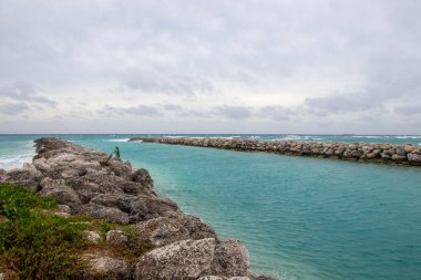 Büyük Bahama Adası 'ndaki okyanus resifi körfezinde bulutlu bir günde dalgalar iskelede kırılıyor.