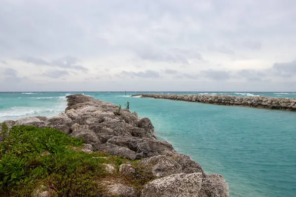 Bulutlu bir günde okyanus körfezi. İskelede dalgalar kırılıyor.