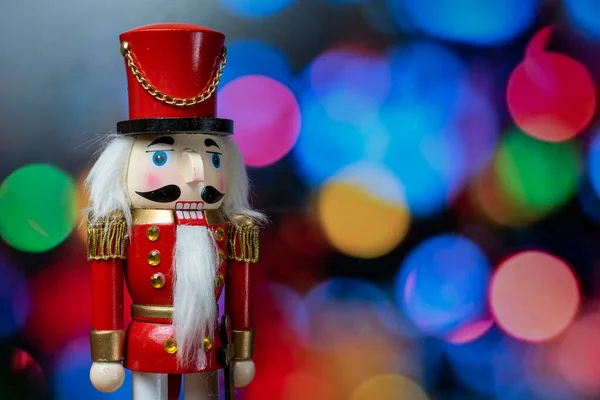 传统的圣诞木制胡桃夹子娃娃 背景上有分散焦点的灯 免版税图库照片