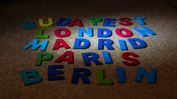 コルクの背景に異なる色の木製の文字で書かれたいくつかのヨーロッパの都市 — ストック写真