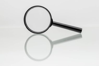 Büyüteç, beyaz arka planı olan bir bardağa yansıtılıyor.