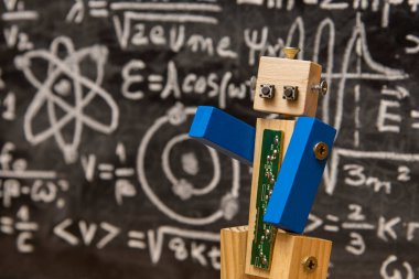 Tahtadan ve vidadan yapılmış robot yazılı formüllerle dolu bir karatahtanın önünde kuantum fiziği öğretiyor.