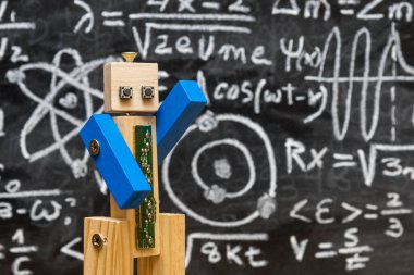 Tahtadan ve vidadan yapılmış robot yazılı formüllerle dolu bir karatahtanın önünde kuantum fiziği öğretiyor.