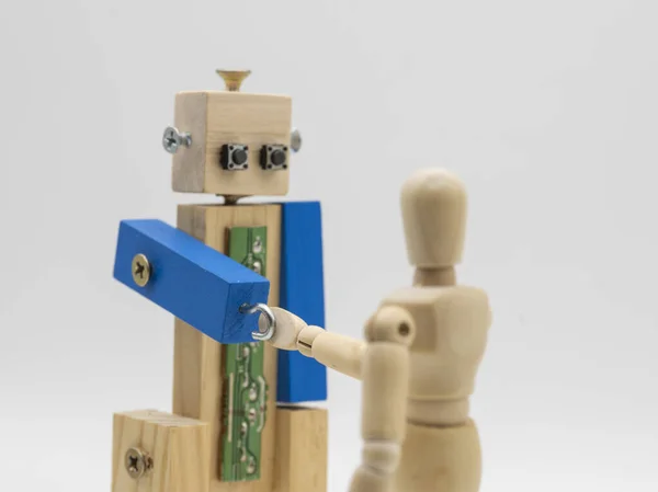 stock image Robot made with wood and screws, shaking hands with a wooden mannequin, isolated on white