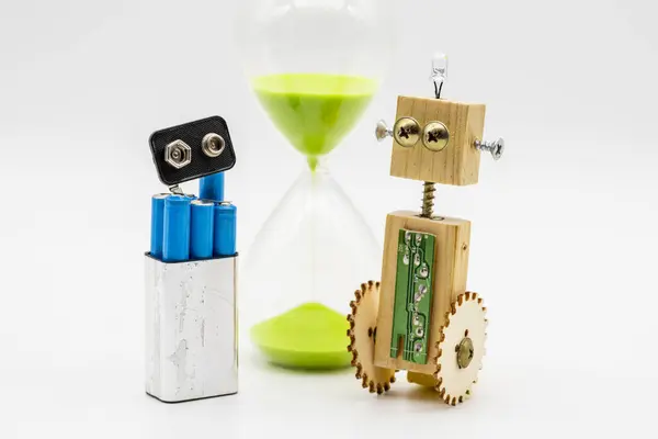 Small robot with wheels, made with wood and screws, and a stack of disassembled flask, isolated on white, with hourglass in the background