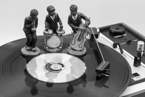 Figures of musicians on a vinyl record on an old record player, black and white