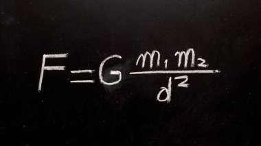 Newton 'un yerçekimi yasası formülü tebeşirle karatahtaya elle yazılmış.