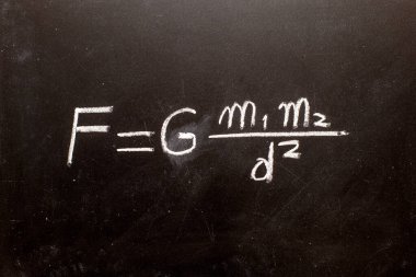 Newton 'un yerçekimi yasası formülü tebeşirle karatahtaya elle yazılmış.