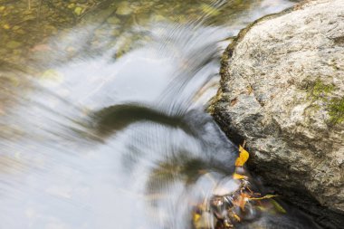 Küçük bir şelalede, ipek yüzeyi ve hareket bulanıklığı olan hızlı bir su akıntısı.
