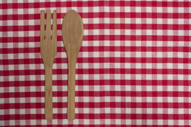 Kırmızı beyaz kareli mutfak masa örtüsü üzerine ahşap çatal bıçak takımı.